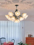 Beside sheer pink-toned curtains and a small dining table, this Clérachic chandelier lights the room from above.