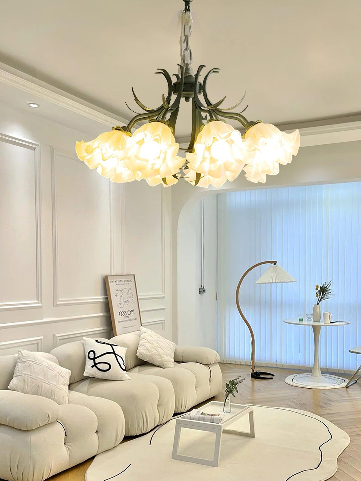 In a panelled living room with sheer curtains, this Clérachic chandelier glows warm above a cream sofa.