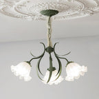 Seen in profile on a grey backdrop, the curved green arms of this Clérachic chandelier hold its shades to one side, unlit.