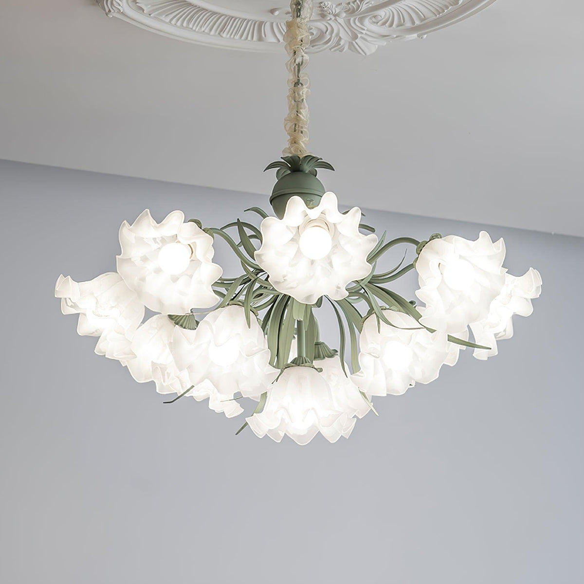 Against a grey backdrop, this Clérachic chandelier's white ruffled shades spread wide, unlit.