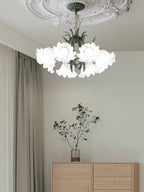 In a minimalist room with dried branches on a sideboard, this Clérachic chandelier hangs unlit near sheer curtains.