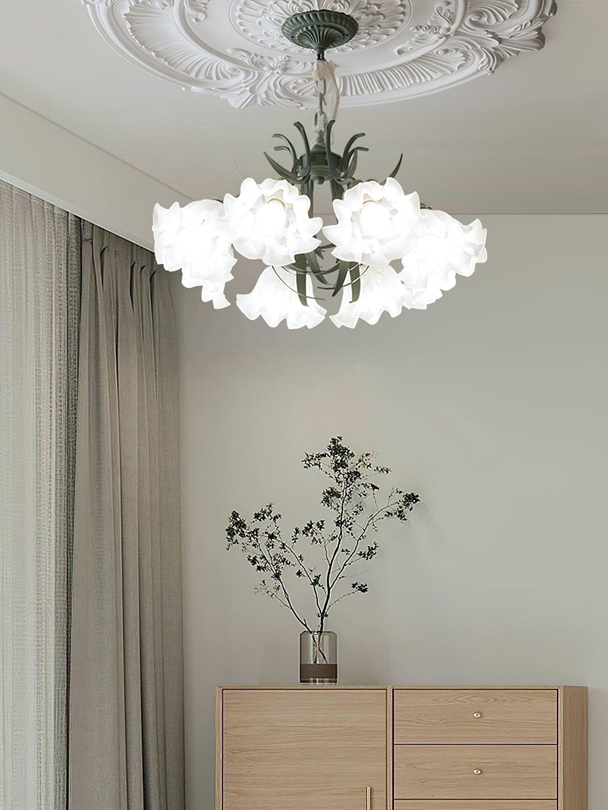 In a minimalist room with dried branches on a sideboard, this Clérachic chandelier hangs unlit near sheer curtains.