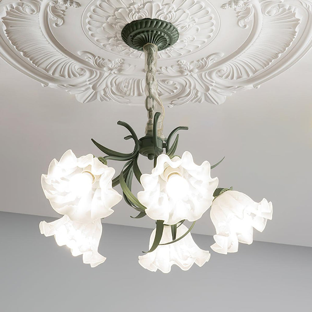 From a low angle on a grey backdrop, the green metal arms of this Clérachic chandelier arch beneath unlit white shades.