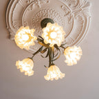 Close beneath an ornate plaster ceiling medallion, this Clérachic chandelier's warm-lit shades fill the frame.