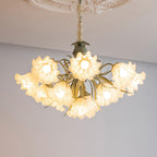 Seen from below on a grey backdrop, this Clérachic chandelier's green stems curve beneath its lit white shades.