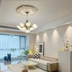 In a modern grey and white living room, this Clérachic chandelier hangs lit above a low sofa.