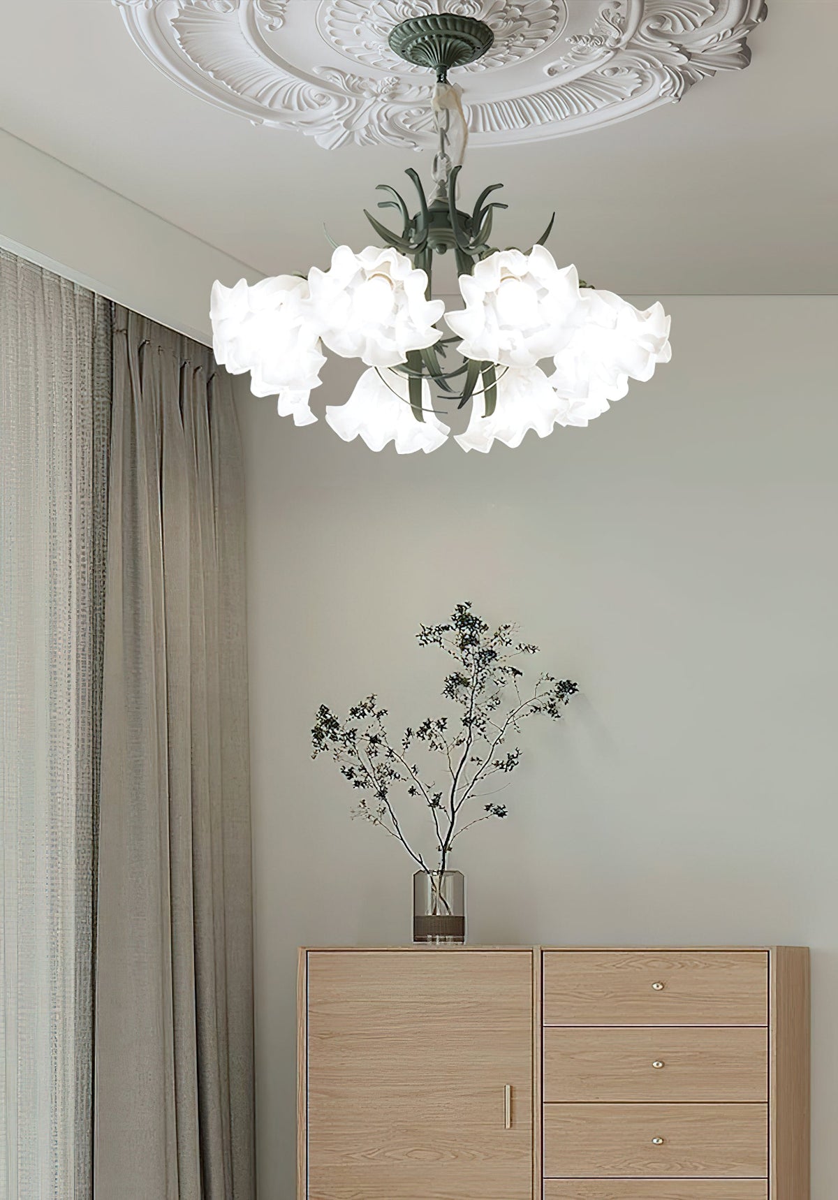 Beside plain wood drawers and taupe curtains, this Clérachic chandelier hangs unlit in a quiet room.