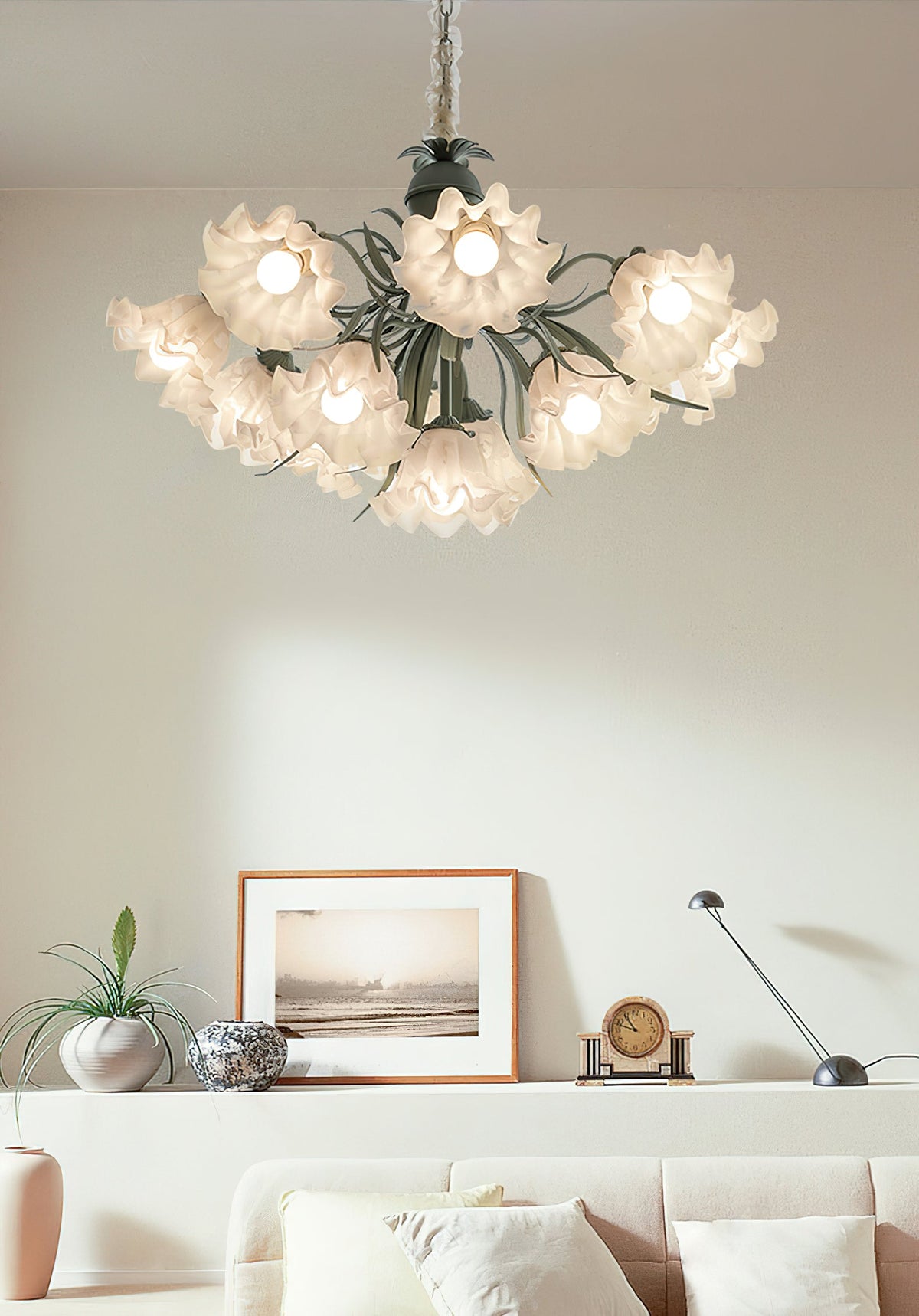 Above a pale sofa and framed print, this Clérachic chandelier glows warm in a bright living room.