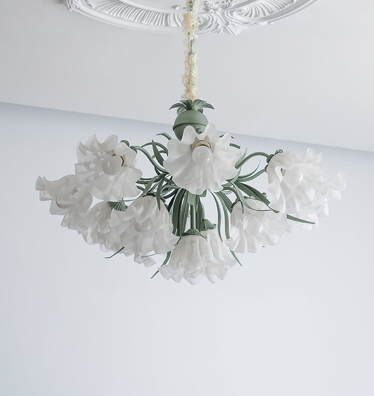On a grey and white backdrop, this Clérachic chandelier's shades spread wide, unlit, around its green frame.