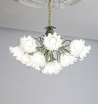 Against a grey backdrop, this Clérachic chandelier's green stems arch out beneath its unlit white shades.