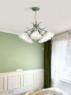 In a green wainscoted bedroom, this Clérachic chandelier lights the space beside a curtained window.