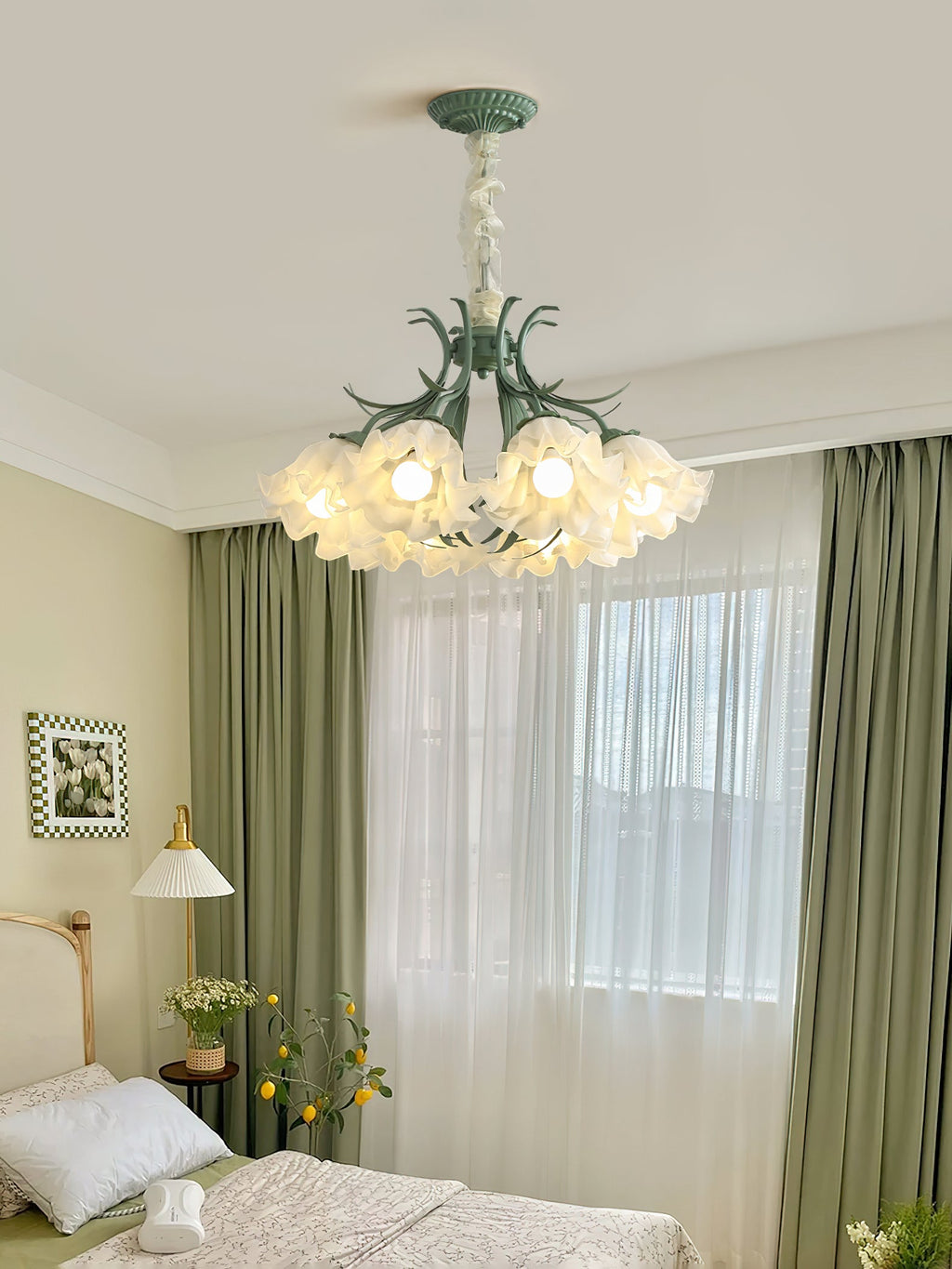 In a bedroom with sage-green curtains, this Clérachic chandelier glows warm above the bed.