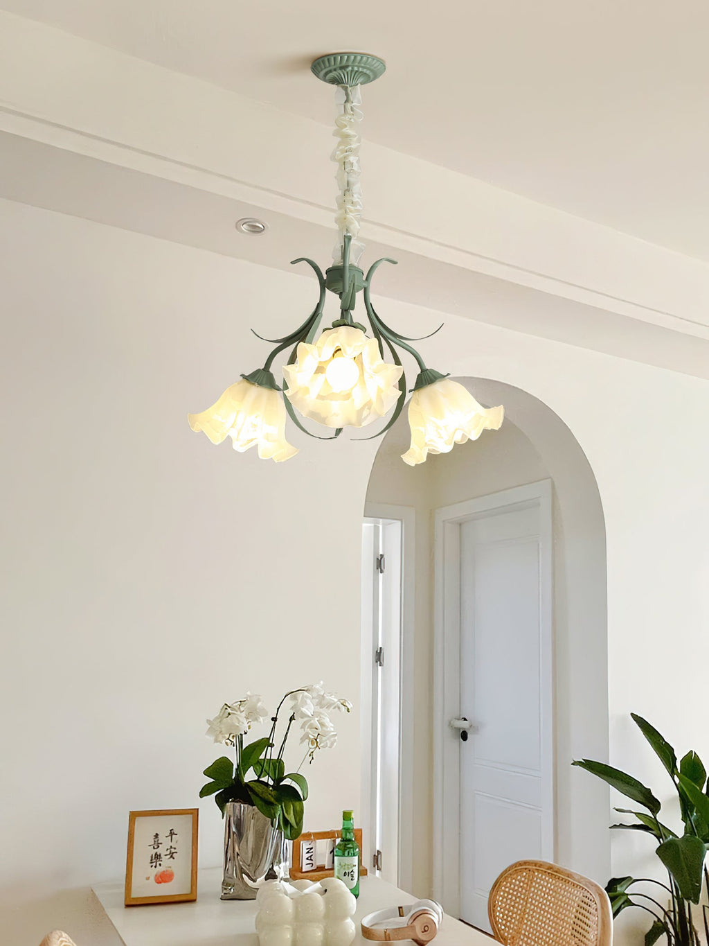 Through a hallway arch past an orchid on a side table, this Clérachic chandelier lights the space.