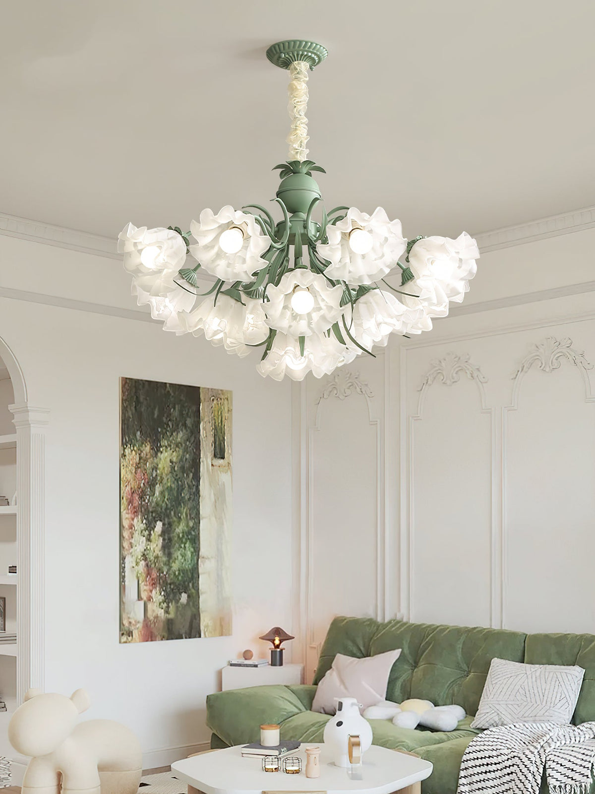 Beneath ornate wall panelling in a living room, this Clérachic chandelier glows above a green sofa.
