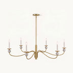 Angled on a plain backdrop, this Clérachic chandelier's brushed brass wave arms and stone ball accents catch the light, unlit.
