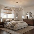 Lit above a grey upholstered bed, this Clérachic chandelier in brushed brass hangs near a round mirror and a wood dresser.