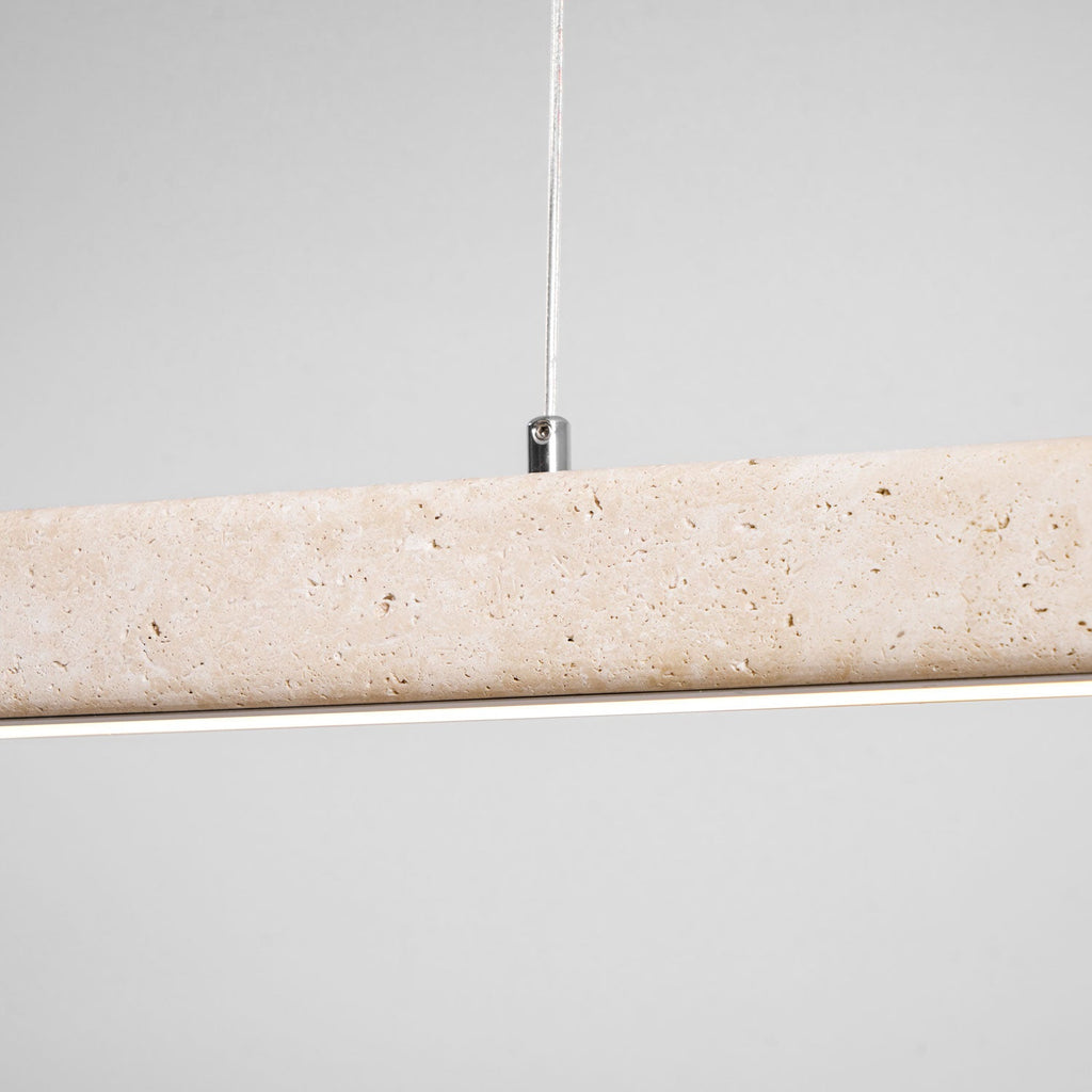 Close view of the travertine's natural pitting on this Clérachic pendant, its LED strip glowing warm along the underside.