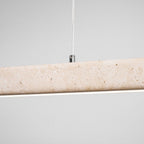 Close view of the travertine's natural pitting on this Clérachic pendant, its LED strip glowing warm along the underside.