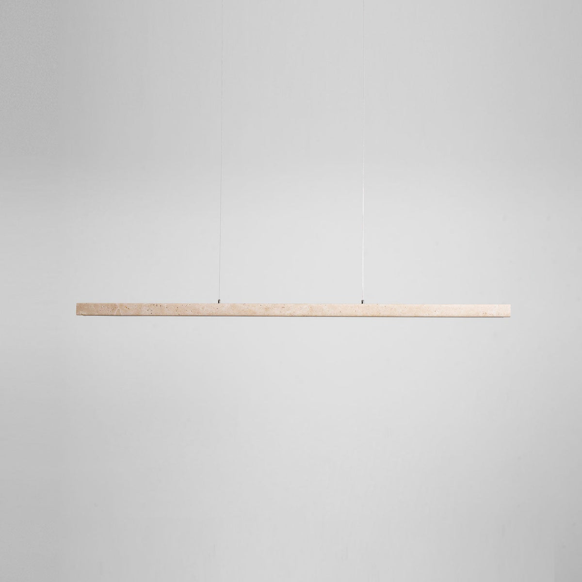 Product-only view of this Clérachic pendant's travertine bar, shown unlit and level against a plain grey backdrop.
