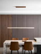 This Clérachic pendant's travertine bar glows evenly above a marble table set for four, against a wood-panelled wall.