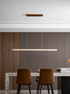 Shown closer above the marble table, this Clérachic pendant's travertine bar glows warm along its full length.