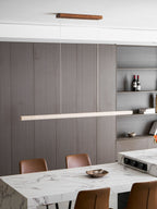 Open shelving with wine bottles sits behind this Clérachic pendant, its travertine bar glowing warm above the marble table.