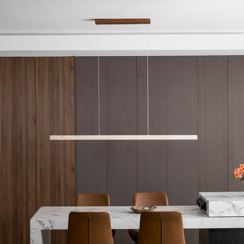 Against a wood-panelled wall, this Clérachic pendant's travertine bar glows softly above a marble table and leather chairs.