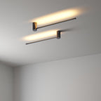 Slim LED tube wall light glowing warm beside a quiet niche