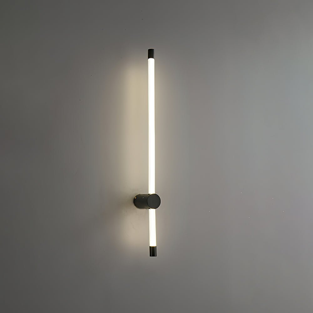 Linear wall sconce mounted beside a quiet bedside niche