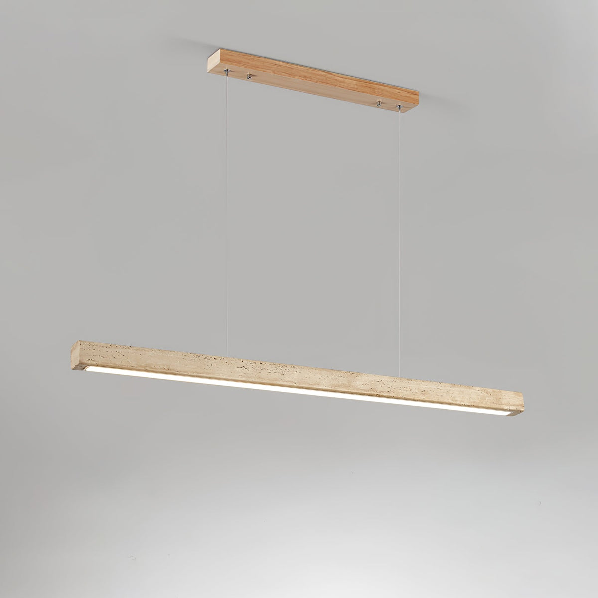 This Clérachic pendant hangs from a pale wood canopy, its travertine bar glowing warm along the underside on a grey backdrop.