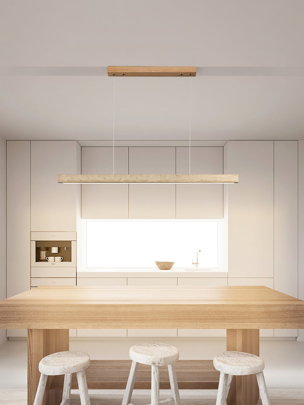 This Clérachic pendant lights a white kitchen, its travertine bar glowing warm above a wood table and three stools.