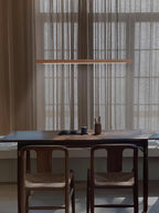 Linear wooden pendant light hanging above a dining table