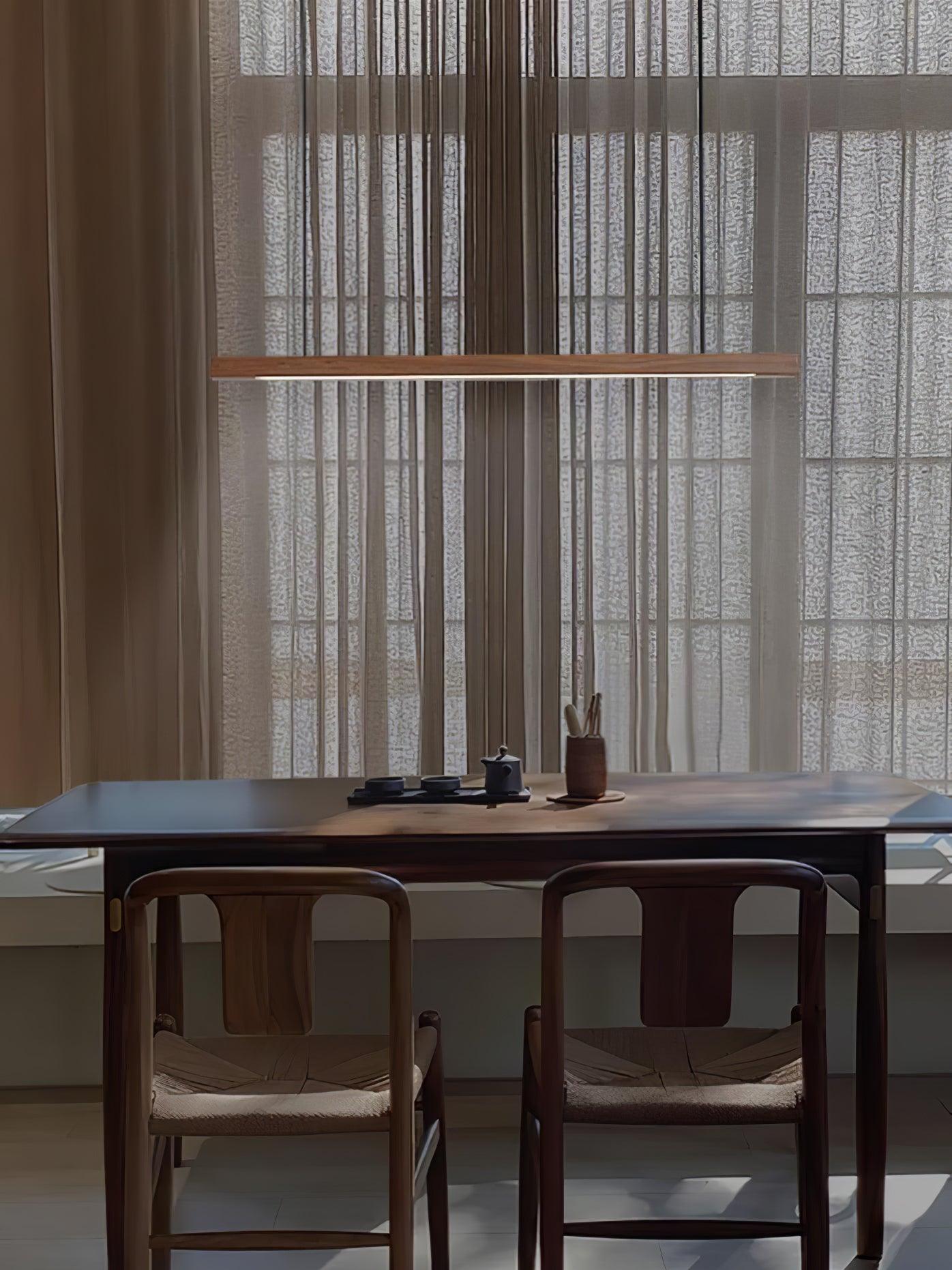 Linear wooden pendant light hanging above a dining table