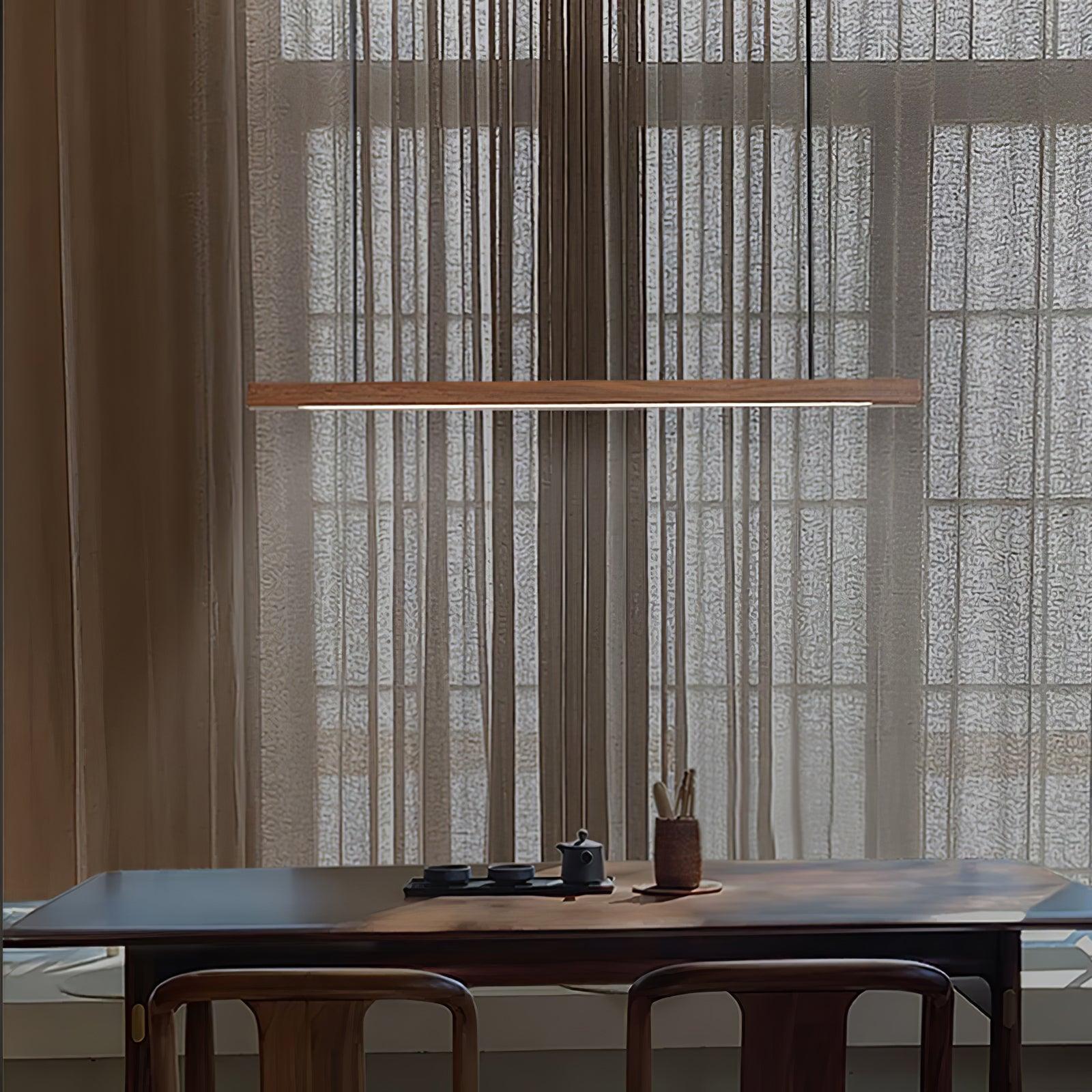 Wooden pendant light slim linear body shown lit warmly