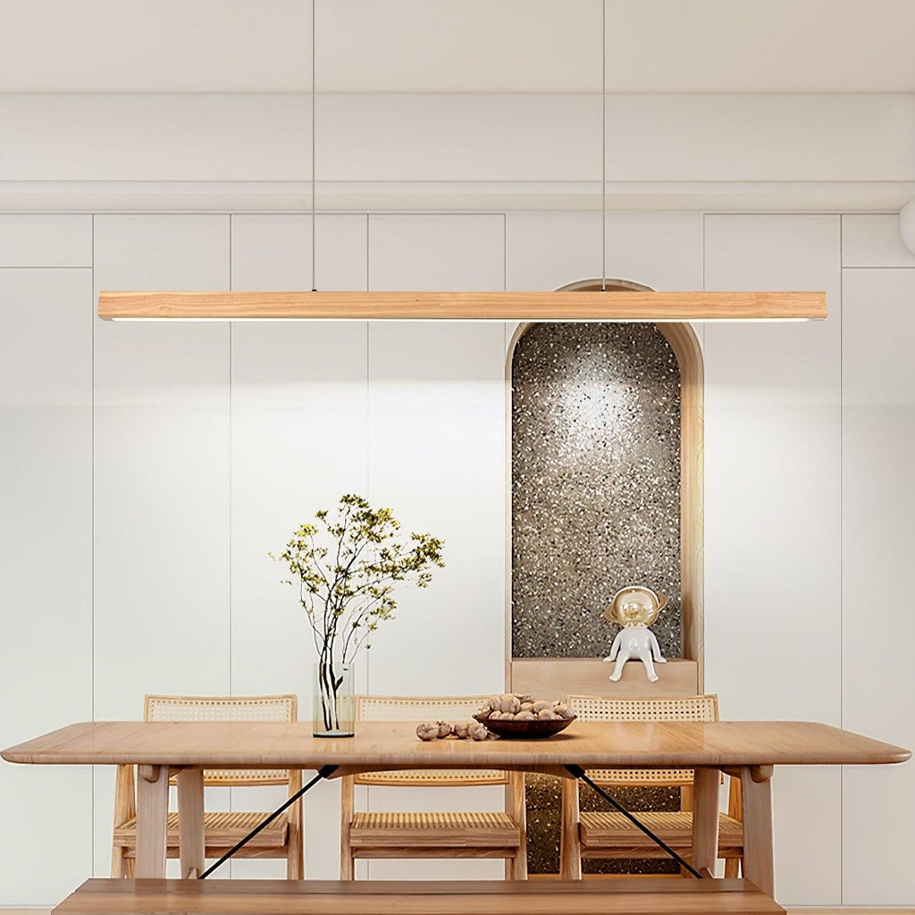 Linear wooden pendant light glowing over a dining space