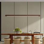 Linear wooden pendant light glowing above a desk workspace