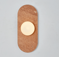 A red travertine Clérachic wall sconce glows alone against a plain wall, its warm stone tone catching the light.
