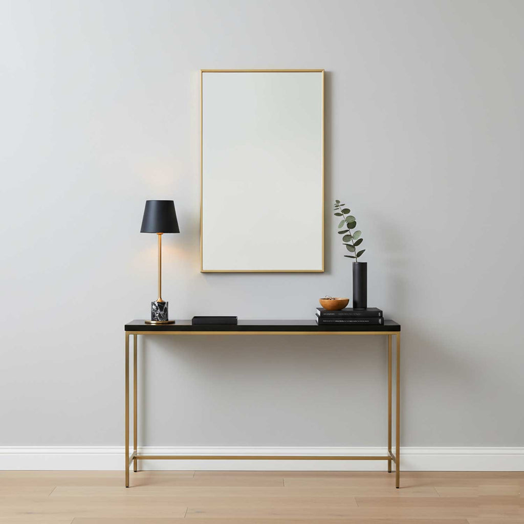 In an entryway vignette, this Clérachic table lamp stands on a black console table beneath a framed mirror, next to a vase and stacked books.