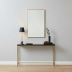 In an entryway vignette, this Clérachic table lamp stands on a black console table beneath a framed mirror, next to a vase and stacked books.