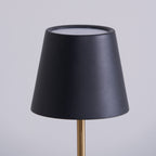 This close-up shows the black tapered shade of a Clérachic table lamp, its pale inner rim catching the light against a soft grey backdrop.
