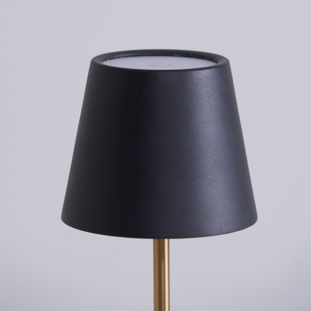 This close-up shows the black tapered shade of a Clérachic table lamp, its pale inner rim catching the light against a soft grey backdrop.