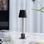 A Clérachic marble table lamp stands on a marble surface near a sheer curtain, a stacked magazine box set beside it.