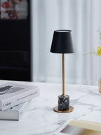 A Clérachic marble table lamp stands on a marble surface beside a sheer curtain, framed straight-on with a magazine box nearby.