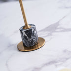 Macro close-up of the marble base and brass foot plate on a Clérachic table lamp, its stem blurred out of focus above.