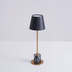 A Clérachic marble table lamp shown against a plain grey studio background, a slightly angled view of the full fixture.