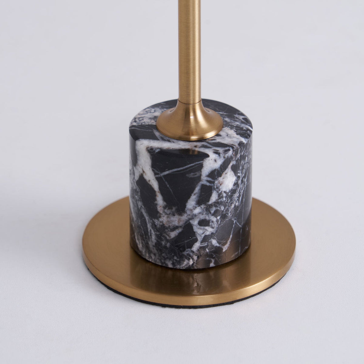 Close-up of the black-and-white marble base on a Clérachic table lamp, showing its veining and the round brass foot plate.