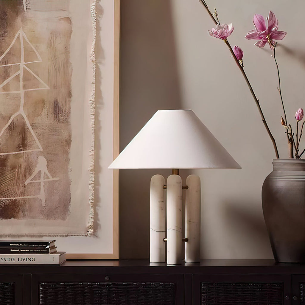 Clérachic table lamp on a dark console beneath a framed abstract painting, a magnolia branch in a vase beside it.