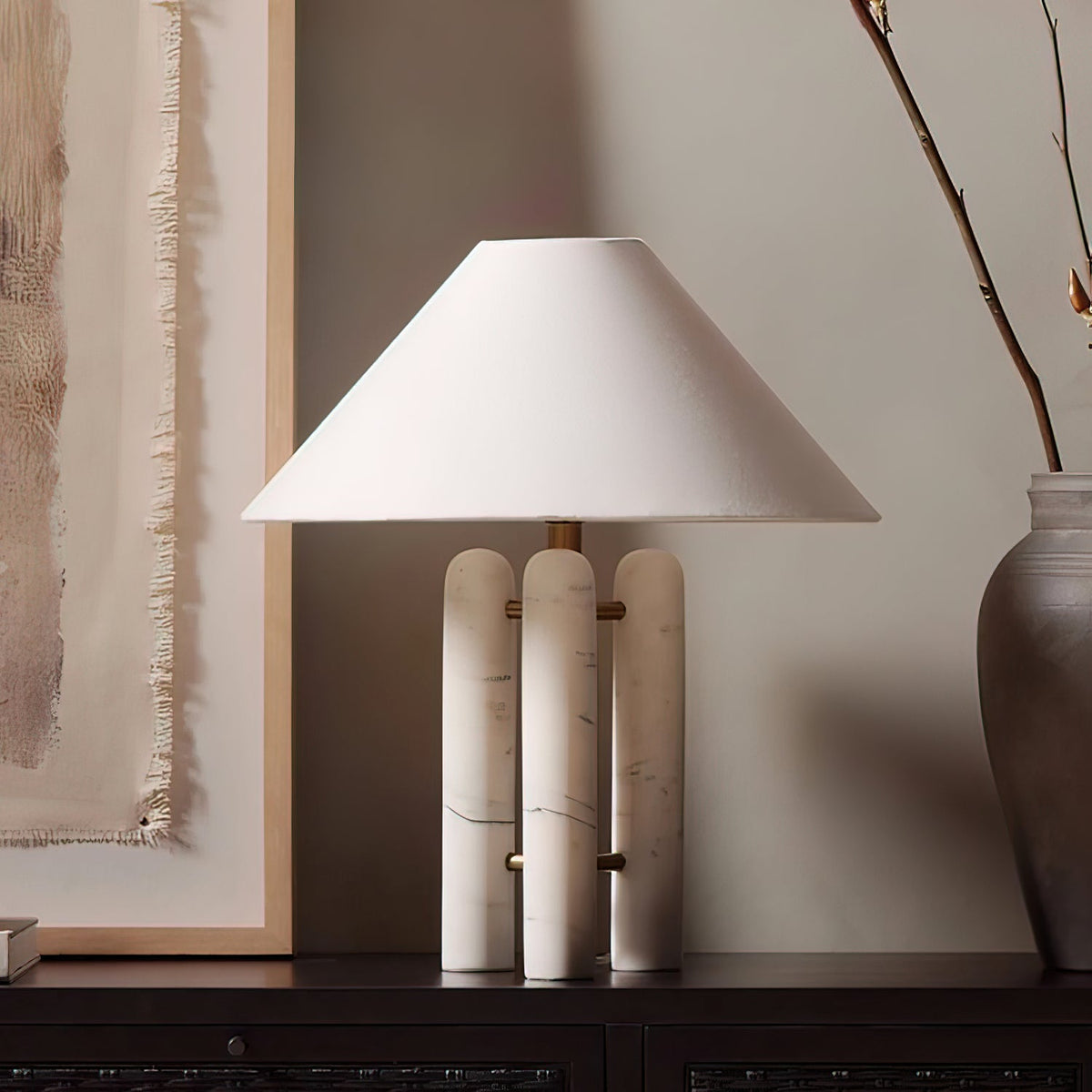 Clérachic table lamp glowing on a dark wood console in a room corner, with framed art and a woven throw nearby.