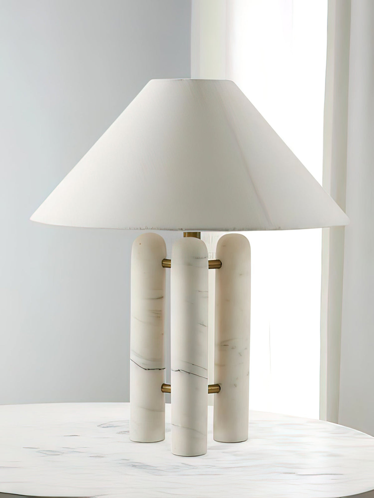 Clérachic table lamp on the marble table, a tall vertical crop emphasising the shade's height above the columns.