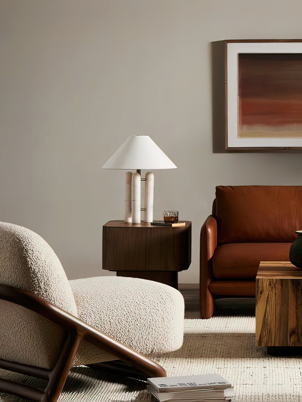 Clérachic table lamp on a dark wood side table in a living room, a cream bouclé armchair and rust sofa nearby.